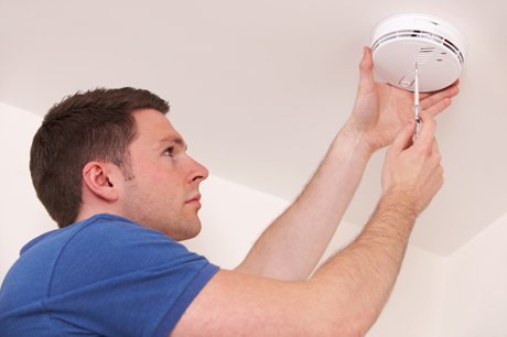 Photo of a man installing a smoke detector