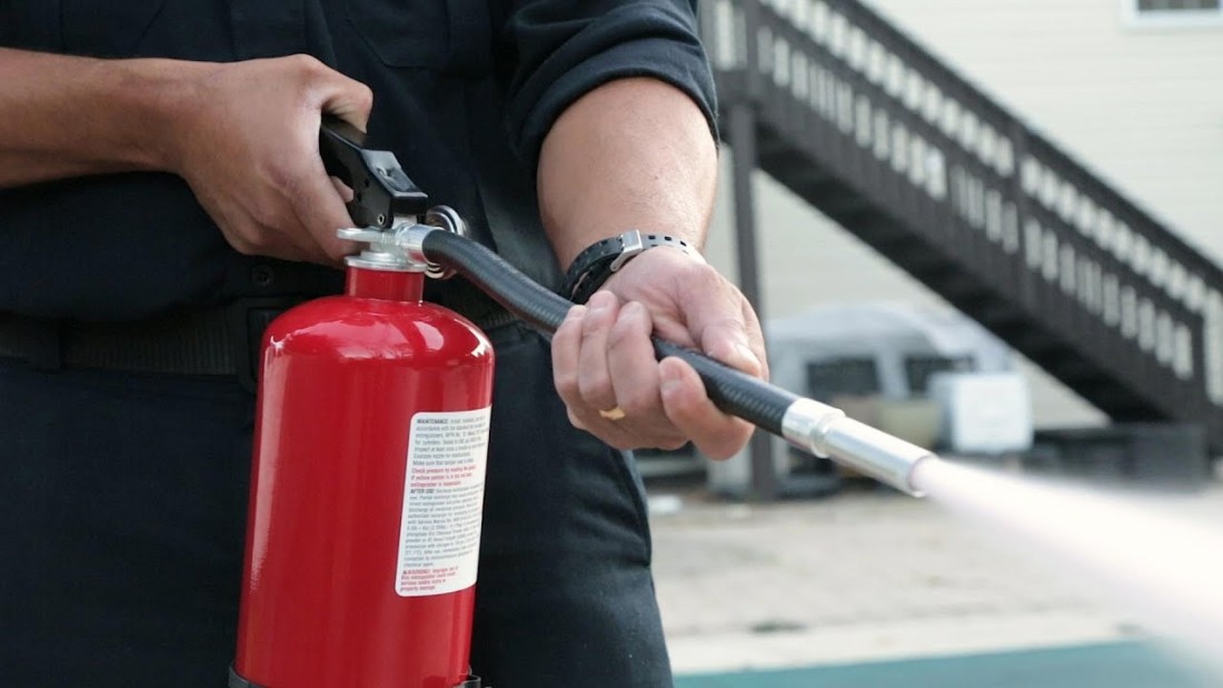 Photo of a man holding a water fire extinguisher